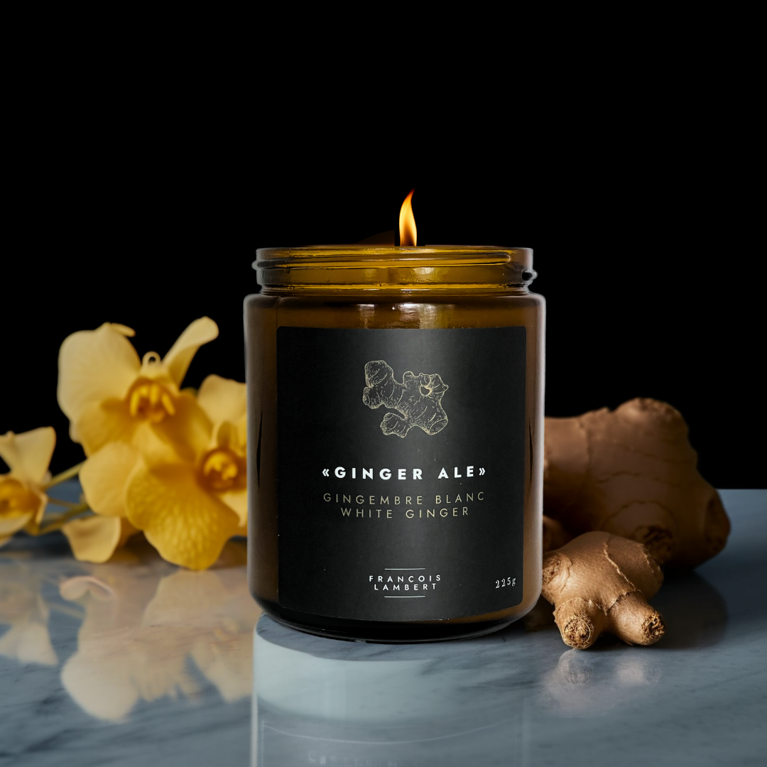 pot de bougie ambré sur une table avec une fleur jaune et du gingembre