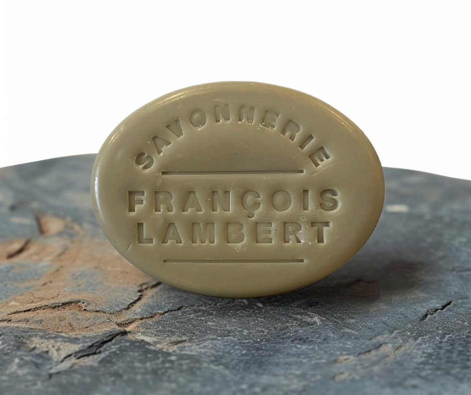 Savon artisanal de la Savonnerie François Lambert posé sur un fond en pierre, gravé avec le nom de la marque, formulé avec du goudron de pin et du lait de brebis pour un soin naturel de la peau.
