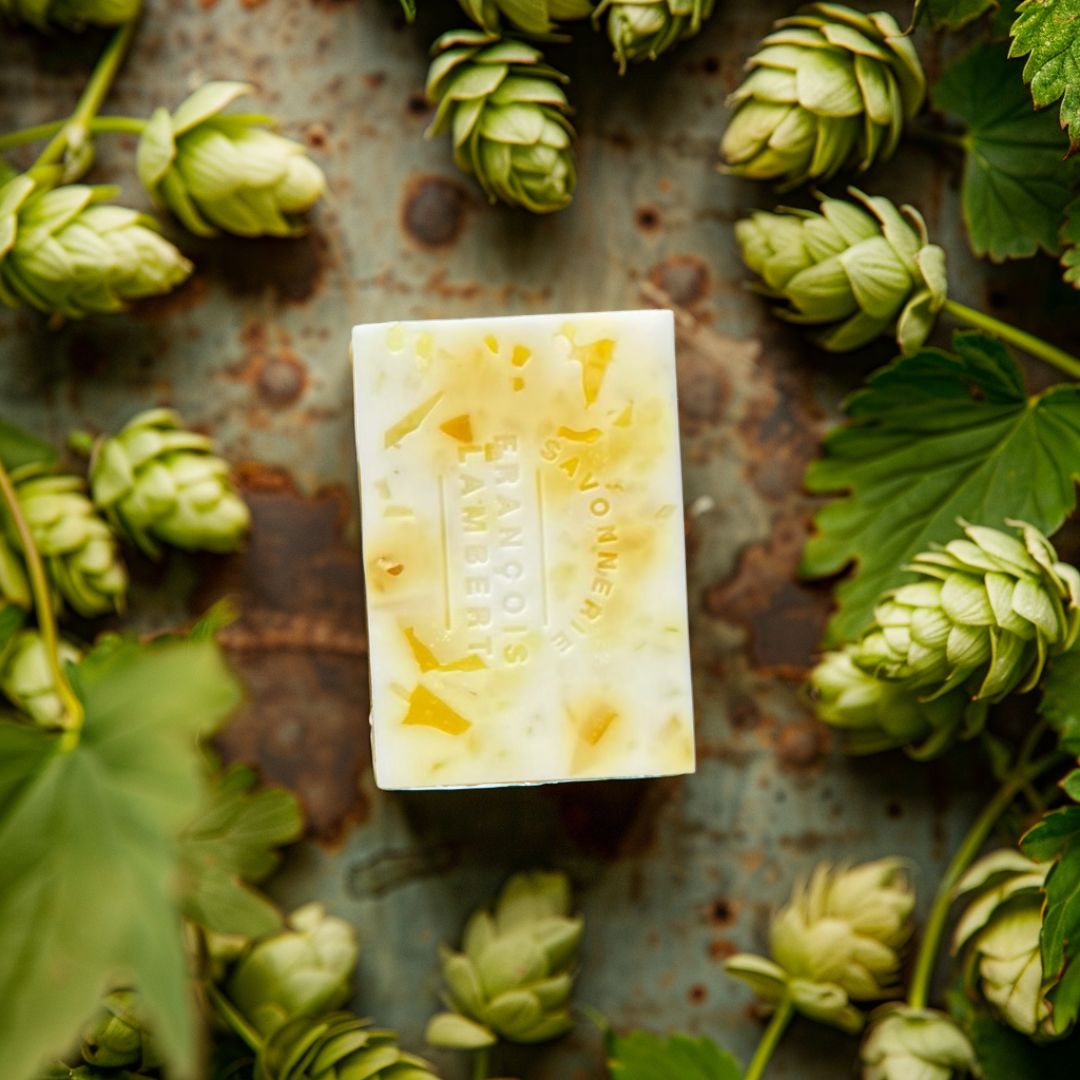 savon blanc et jaune à la bière fruitée sur un comptoir entouré de houblon