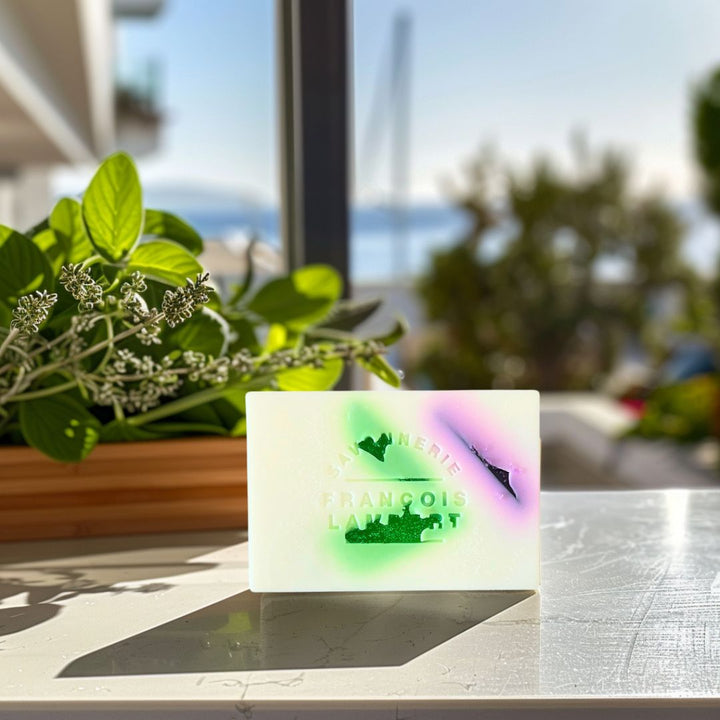 savon au lait de brebis sur un comptoir ensollé. Le savon est au lait de brebis et à la fragrance de sauge, romarin et basilic. Le savon est blanc avec du vert et du rouge