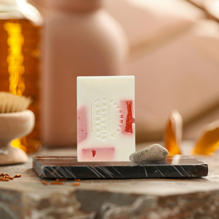 savon au lait de brebis blanc, fragrance ambre et romance sur une plaque de marbre avec du ambre derrière